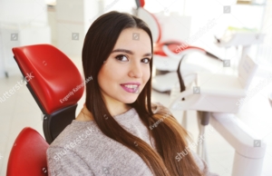 beautiful-young-brunette-girl-in-red-dental-chair-smiling