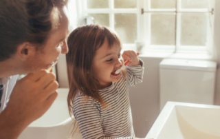 father with cavities and daughter brushing teeth
