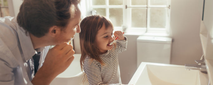 father with cavities and daughter brushing teeth